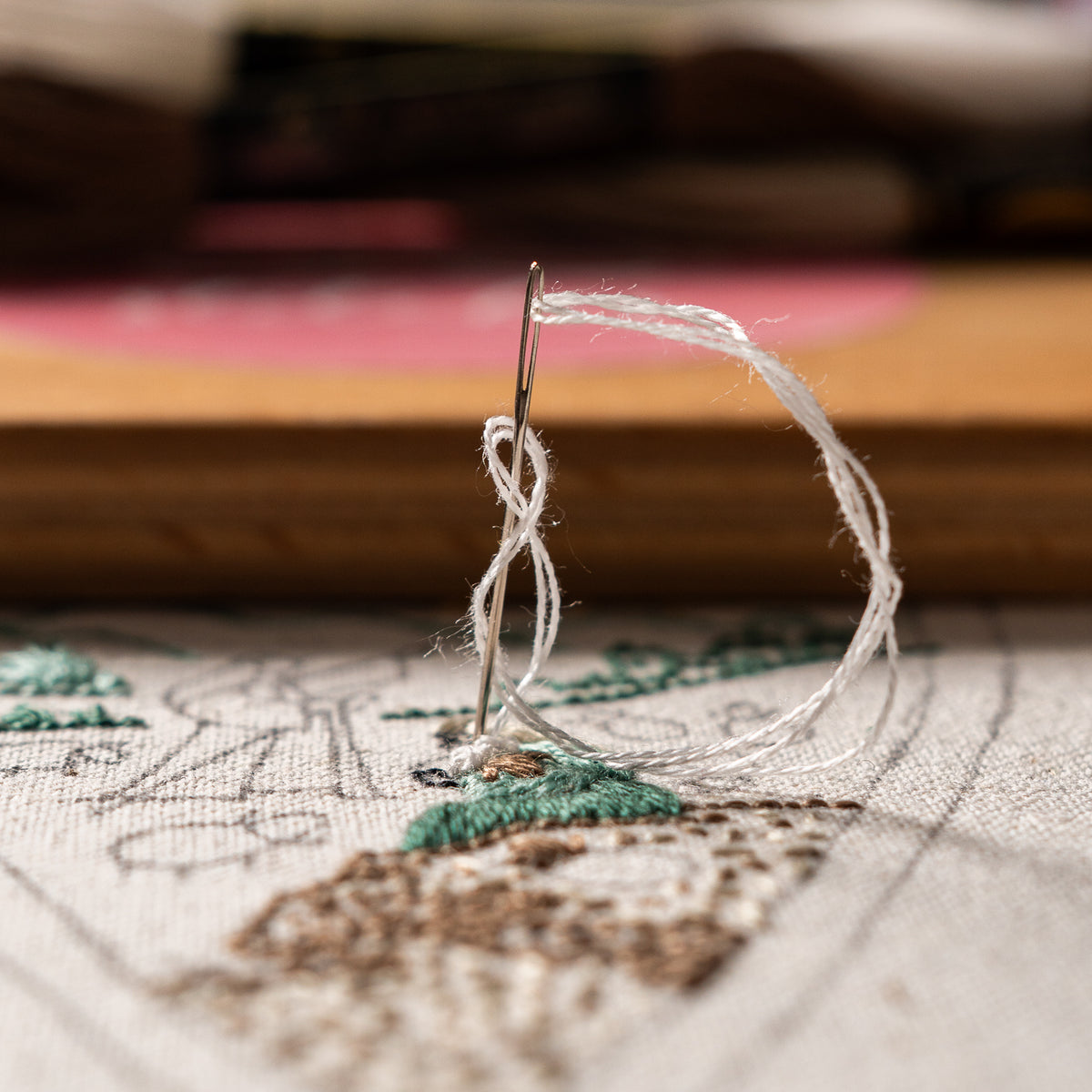 Close-up of white embroidery thread and needle stitching a sheep on fabric for The Shepherds of Bethlehem Christian Christmas embroidery pattern.