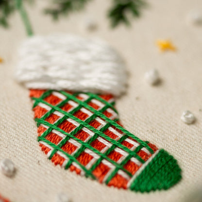 May include: Close-up of a red and green embroidered Christmas stocking with a white fluffy cuff.