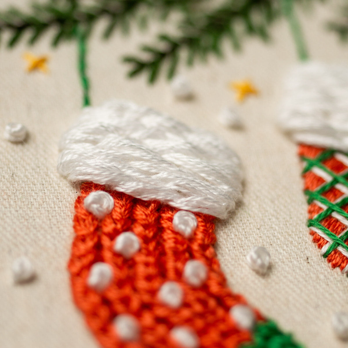 May include: Close-up of a hand-stitched Christmas stocking with a white pom-pom on top and red and white knit details.