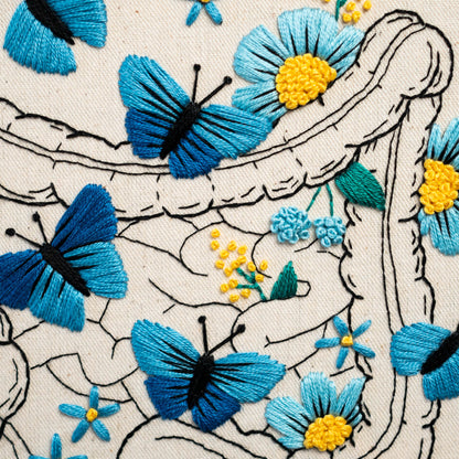 May include: Embroidered design of a human intestine with blue butterflies and flowers. The intestine is outlined in black thread and the butterflies and flowers are filled in with blue thread.