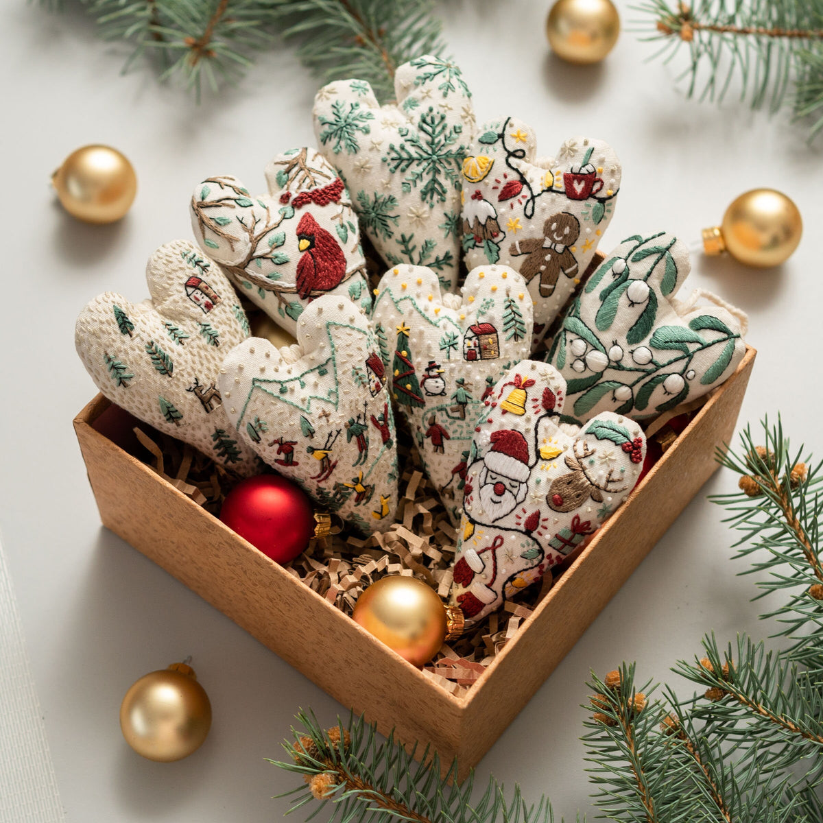 May include: A set of 10 handmade felt heart ornaments in a brown box. The hearts are decorated with various Christmas themes, including snowflakes, holly, and Santa Claus.
