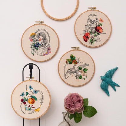 May include: Four embroidery hoops with different anatomical organs embroidered with colorful flowers. The organs include a kidney, a liver, a larynx, and a stomach.