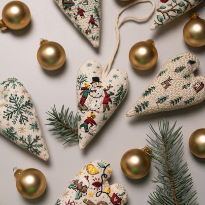 May include: A collection of six handmade heart-shaped ornaments with embroidered winter scenes. The ornaments are made of white fabric with green, red, and brown embroidery. The ornaments are decorated with gold beads and are surrounded by gold orna