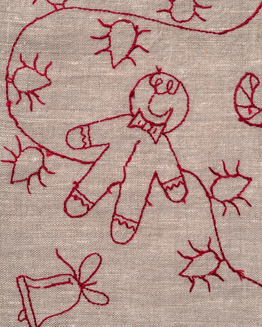May include: Close-up of a beige fabric with red embroidery. The embroidery features a gingerbread man, a bell, and other festive shapes. The stitches are visible, creating a textured effect. The design is likely for a holiday-themed item.