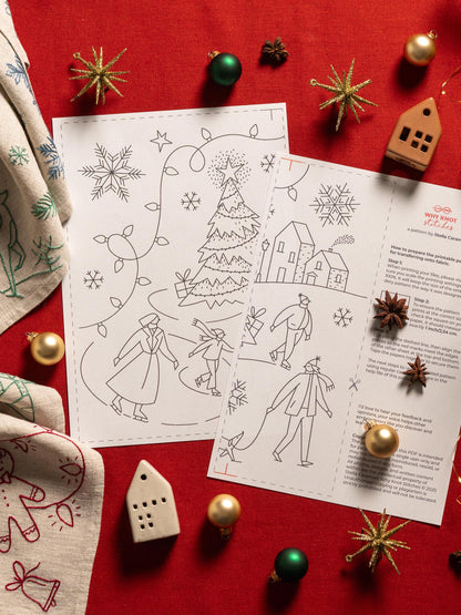 May include: Two black and white Christmas-themed embroidery patterns with illustrations of a Christmas tree, houses, and people ice skating. The patterns are surrounded by Christmas ornaments and decorations on a red surface.