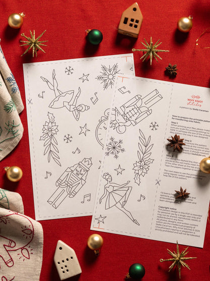 May include: Two white printable patterns with black line drawings of ballerinas, snowflakes, and a nutcracker. The patterns are surrounded by Christmas ornaments and decorative items on a red surface. The text "WHY KNOT stitches" is visible.